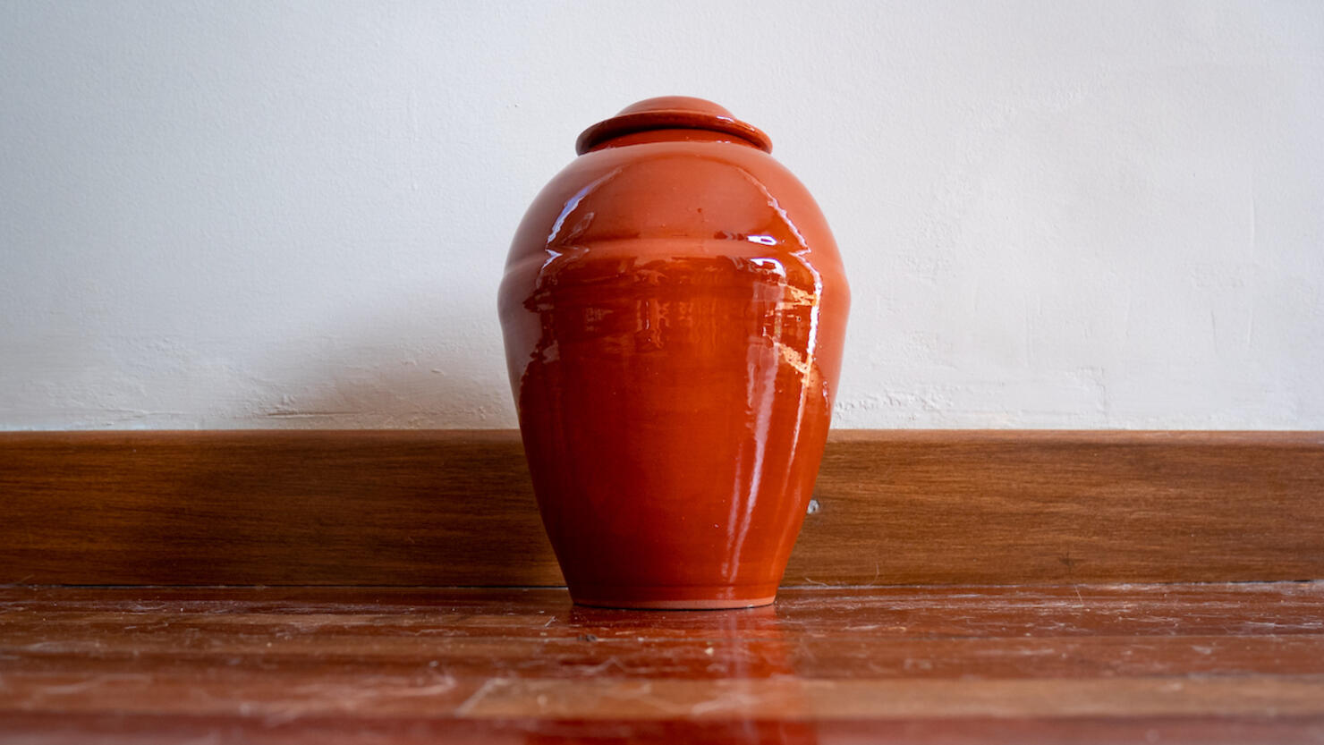 Orange Urn Leaning Against the White Wall