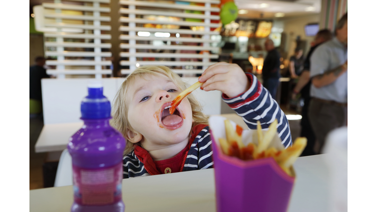 Toddler eating fast food in restaurant