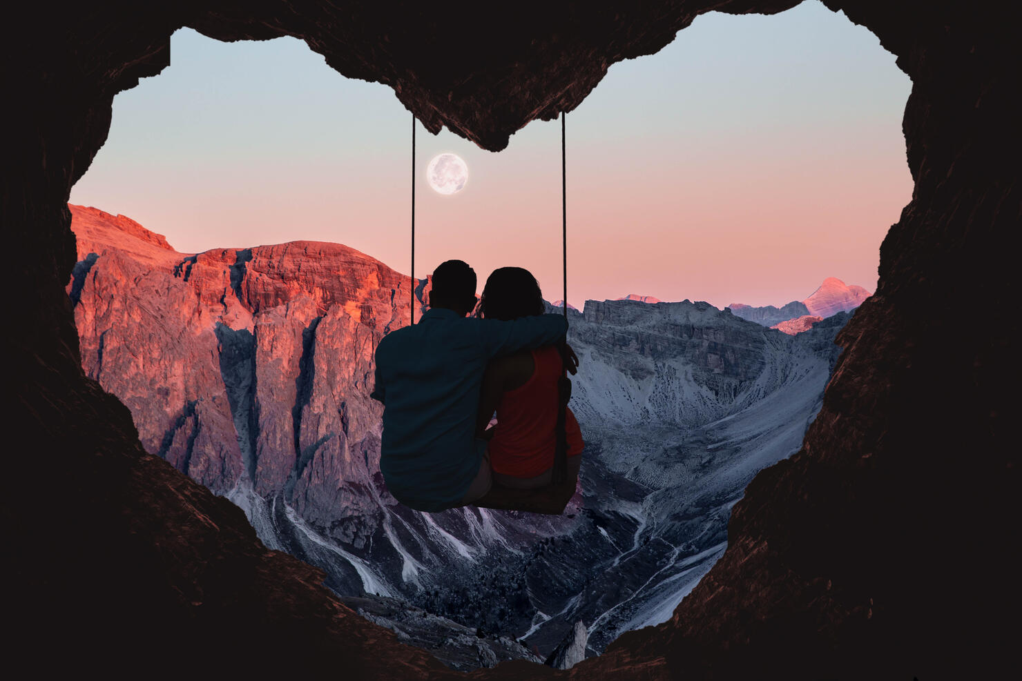 Couple on swing contemplating the mountains in a romantic view with heart shape.