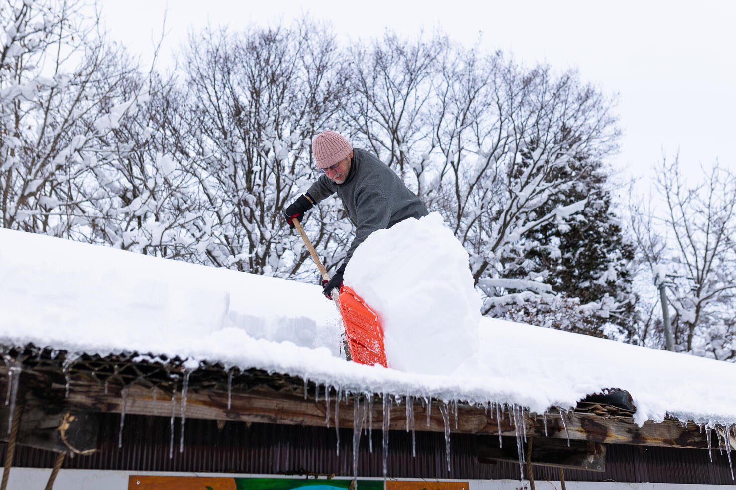 Senior man shoveling snow off roof