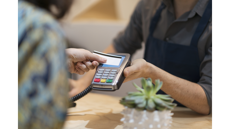 Woman paying with contactless credit card in flower shop