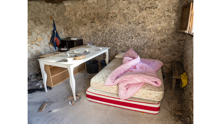 Dirty room in ruins, with a mattress and kitchen equipment invaded by squatters.