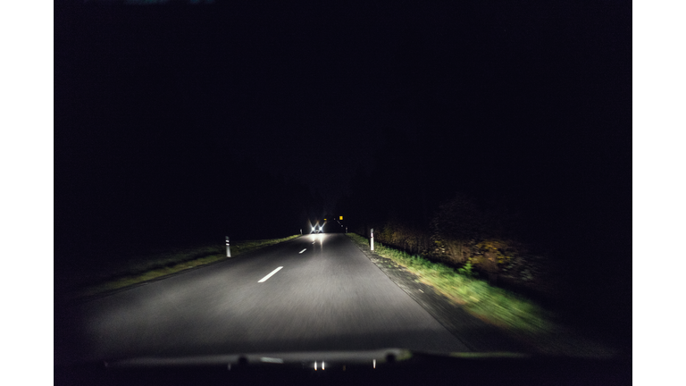 Dark street at night with oncoming traffic