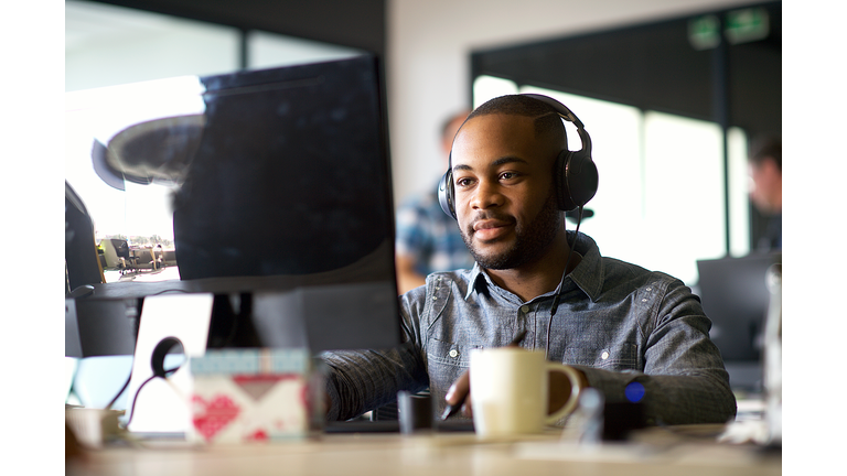 Young African Man with headphones looking at a computer monitor