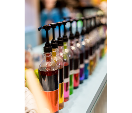 Row of pump head bottle of beverage in the cafe. Soft focus