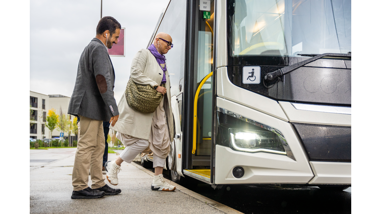 Mid adult man and woman boarding bus, side view