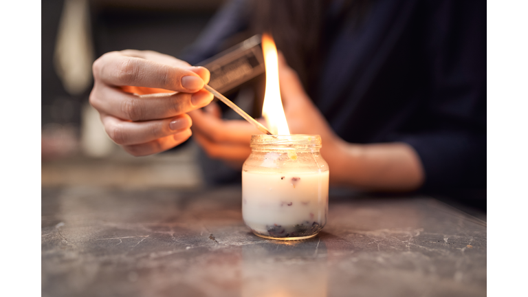 Crop lady lighting fragrant candle placed on table