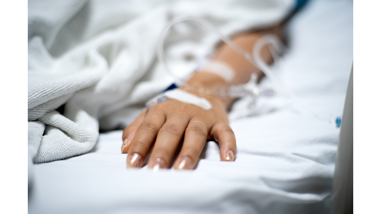 Girl patient with IV drip medicine attached in hospital