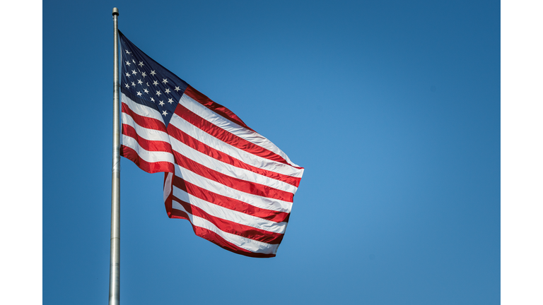 USA American flag flying against Blue Sky