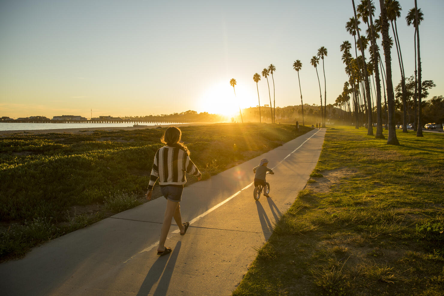 A mother and her son riding a bike near a beach in California