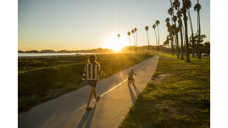 A mother and her son riding a bike near a beach in California