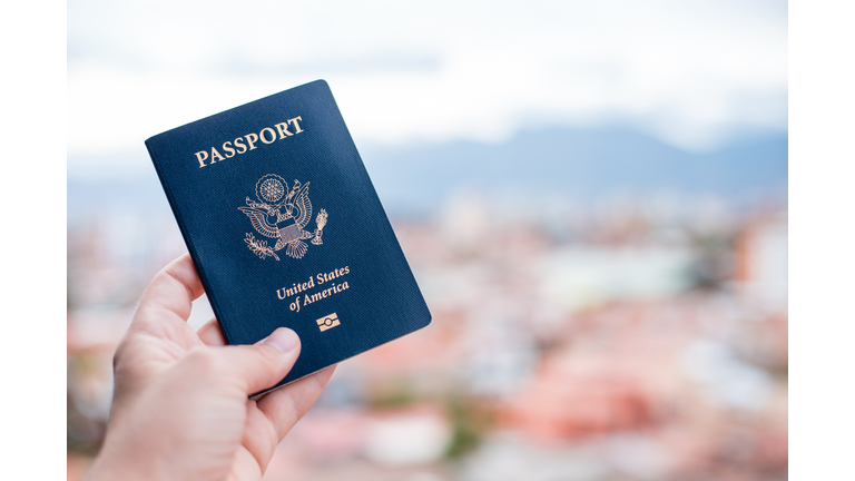 Close-Up Of Hand Holding American Passport Against Townscape