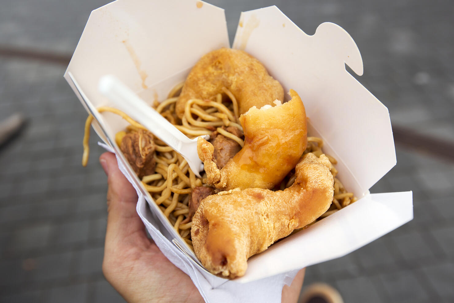 Eating Chinese food from takeaway box on the street, personal perspective