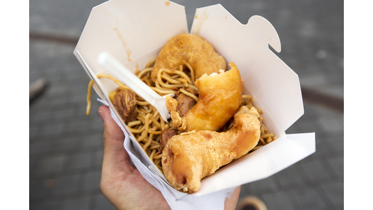 Eating Chinese food from takeaway box on the street, personal perspective
