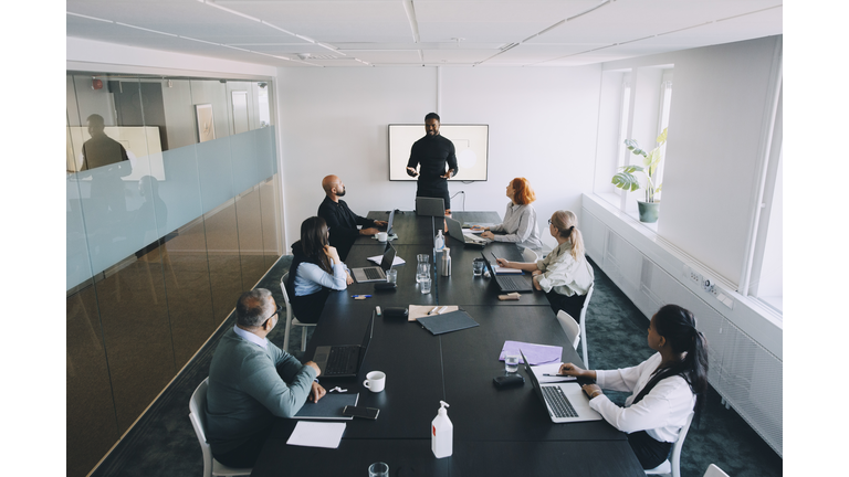 High angle view of businessman giving presentation colleagues in board room at office