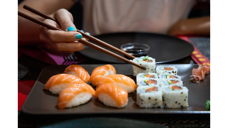 Eating Sushi with chopsticks in Japanese restaurant.