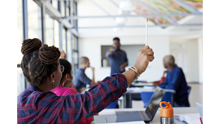 Woman with hand raised holding pencil