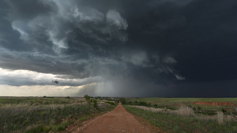 A red dirt road leads into a Tornado warned severe thunderstorm, Waynoka, Oklahoma. USA