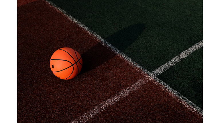 Outdoor basketball court in the courtyard. A basketball is lying on the ground, a sports field, on a sunny summer day. The concept of sports and a healthy lifestyle. Space for copying.