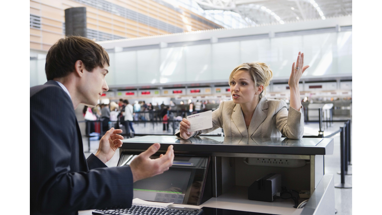 Upset businesswoman checking in at airport ticket counter