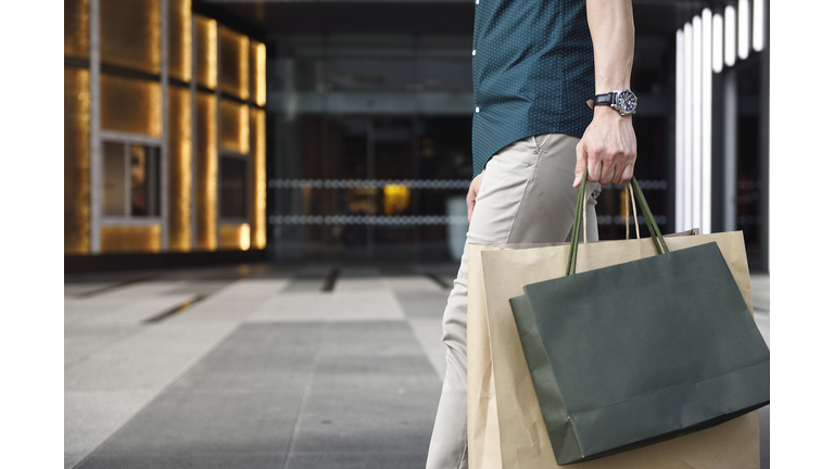 Man's legs and shopping bags outside a luxury mall