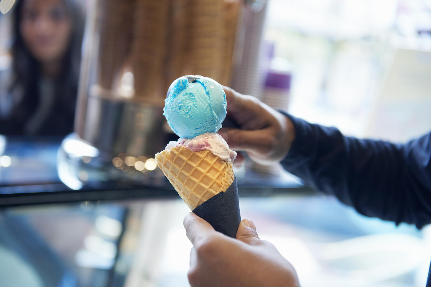 Man scooping ice cream onto cone
