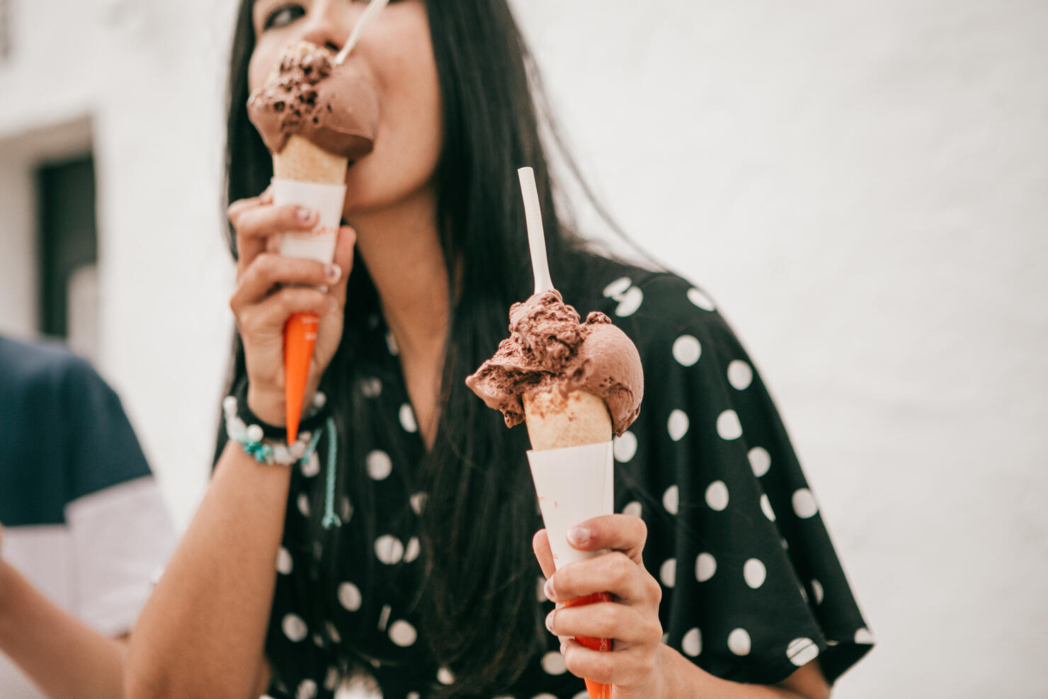 pretty latina stands on street holding melting chocolate cone ice cream
