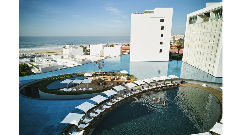 Wide shot aerial view of family playing in pool at tropical resort