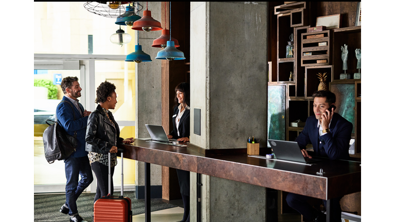 Businessman and woman checking in to hotel reception
