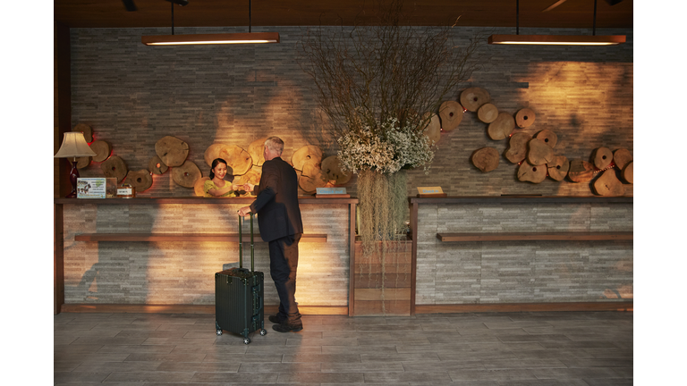 Man giving passport to receptionist in lobby