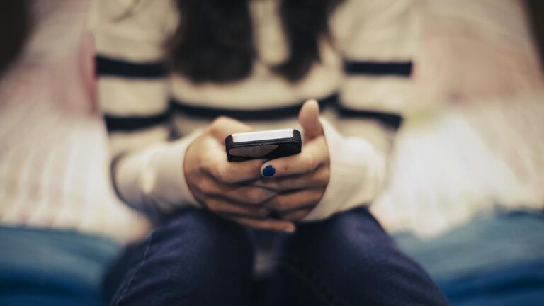 Close up of teenage girl in bedroom using smart phone