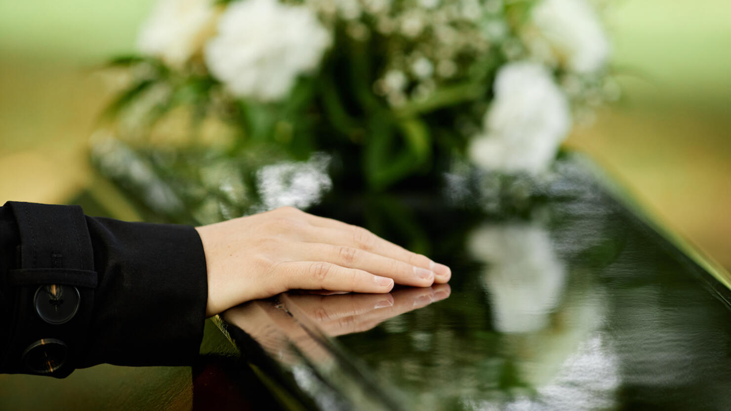 Close up of female hand on coffin
