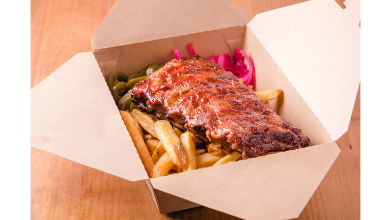 Spicy hot grilled spare ribs from a BBQ served with french fries ready to take away