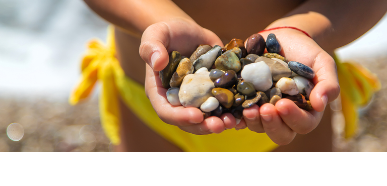 A child on the beach holds sea stones in her hands Selective focus