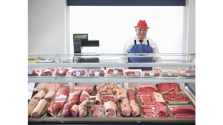 Butcher standing behind meat counter