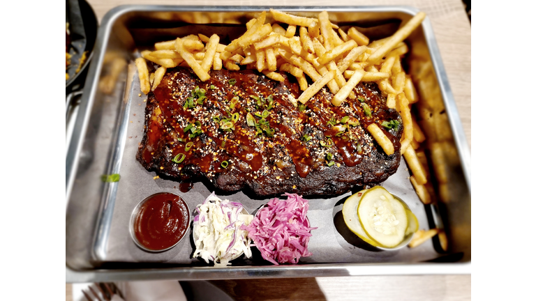 Grilled beefsteak and French fries served in a stainless steel tray.