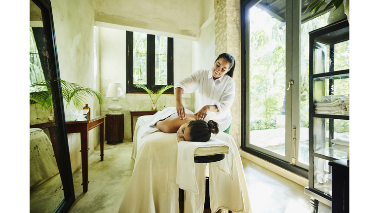 Wide shot of woman receiving massage at luxury spa