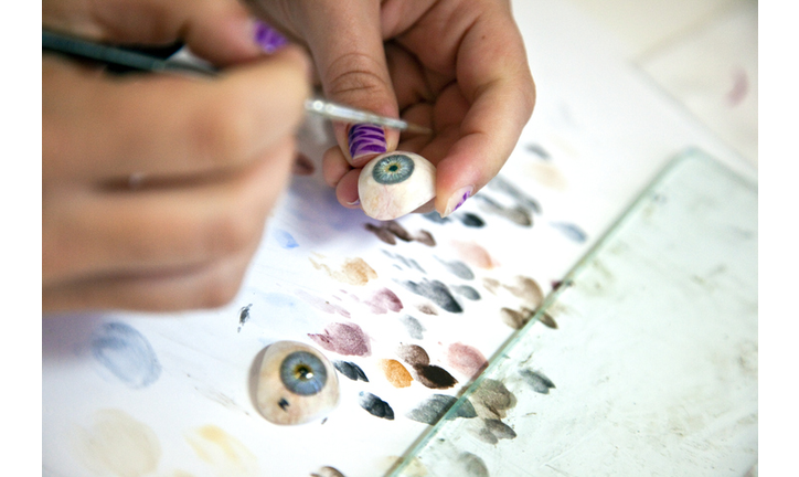 A woman painting blue prosthetic eyes