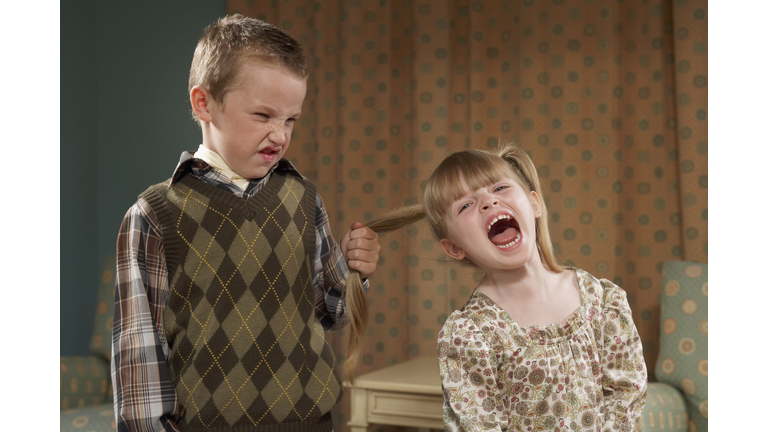 Boy (6-7) pulling girl's (4-5) hair in room