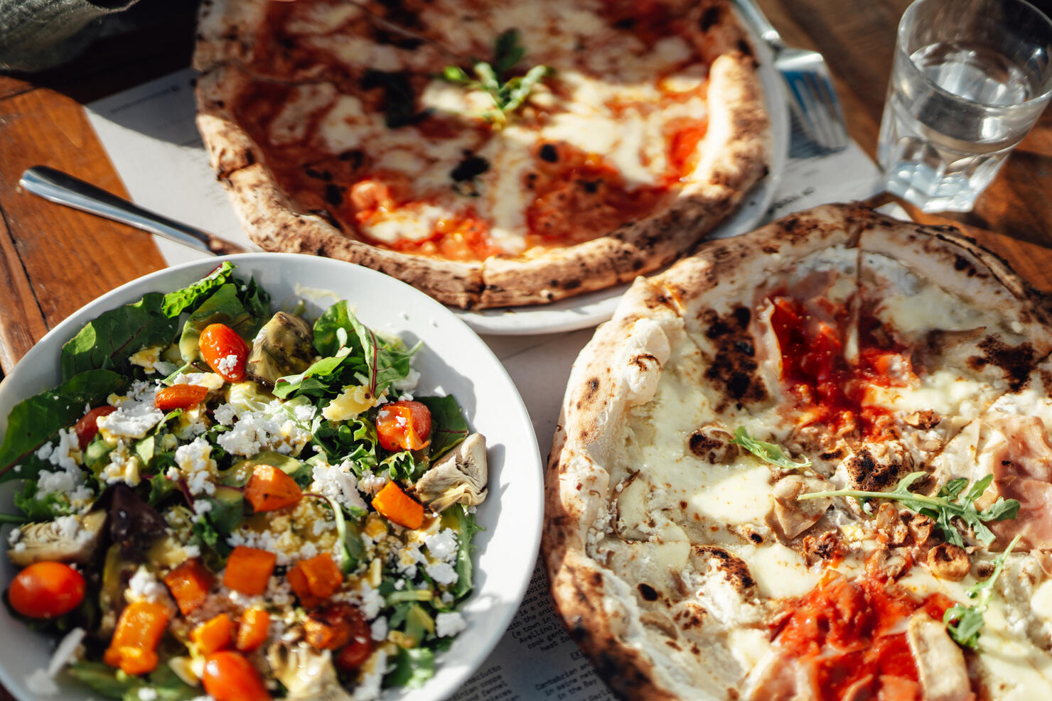 Elevated view of fresh pizza and green salad served on the table at outdoor restaurant