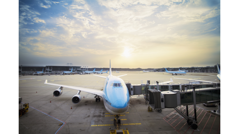 Airplane parked at gate at sunset