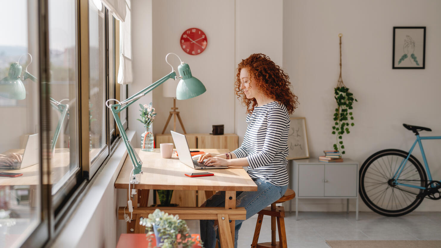 Woman sitting on a desk using a laptop computer while working from home.