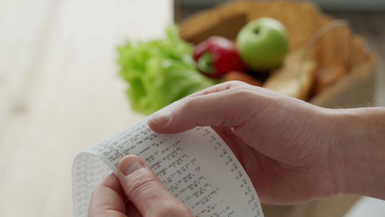 Close-up woman looking a check from a supermarket. Expense tracking and budgeting