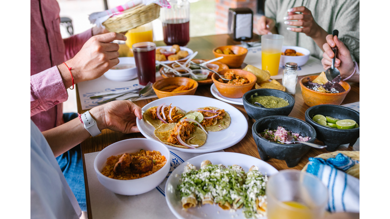 group of Friend eating Mexican Tacos and traditional food, snacks and peoples hands over table, top view. Mexican cuisine