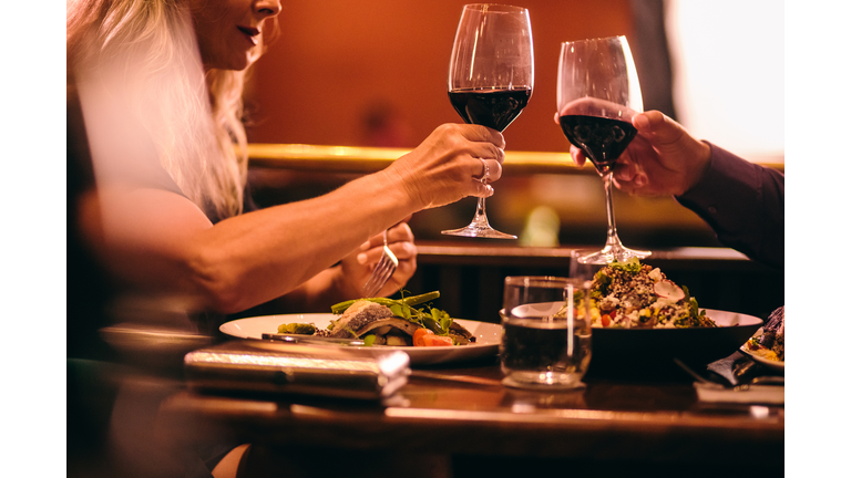 Elegant mature couple dining and toasting with wine at restaurant