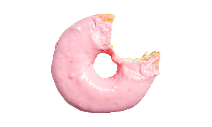 Pink strawberry donut with bite missing isolated on white background