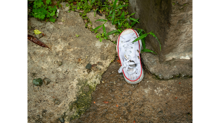 An Old White Sports Shoe Lying in the Street