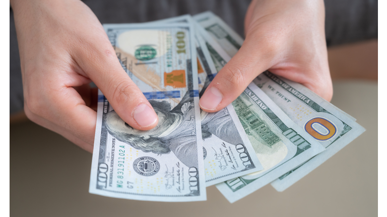 Close up of someone hands holding and counting American dollar banknotes in her hand.