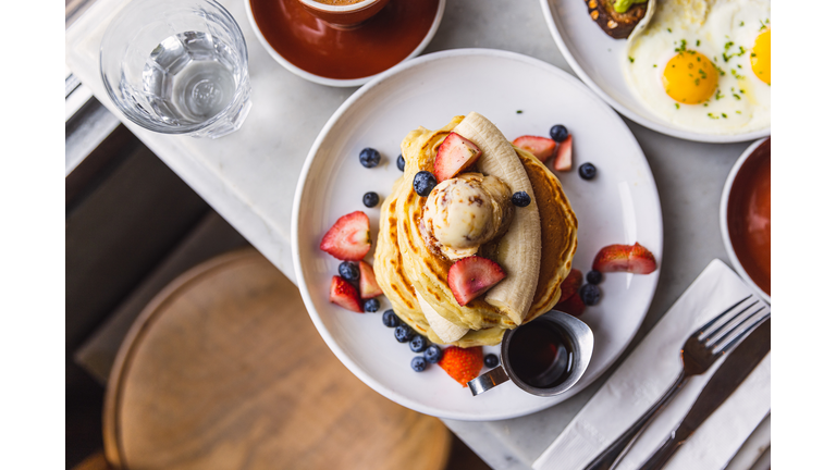Pancakes with banana, strawberry and blueberry served in a cafe for breakfast, high angle view