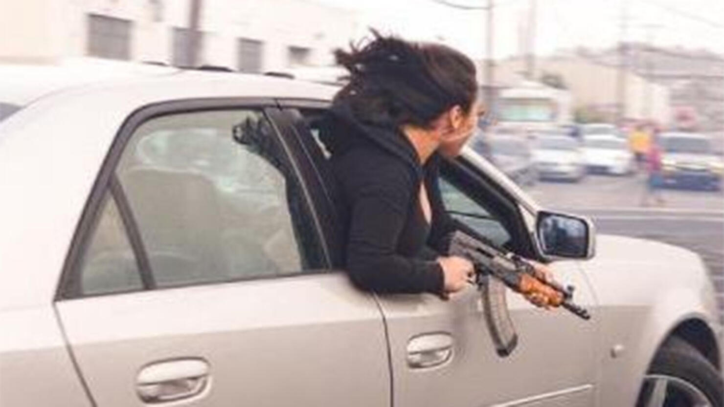 Woman holding an AK-47 out of a car window